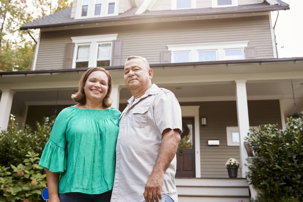 portrait of smiling senior couple in front of their home